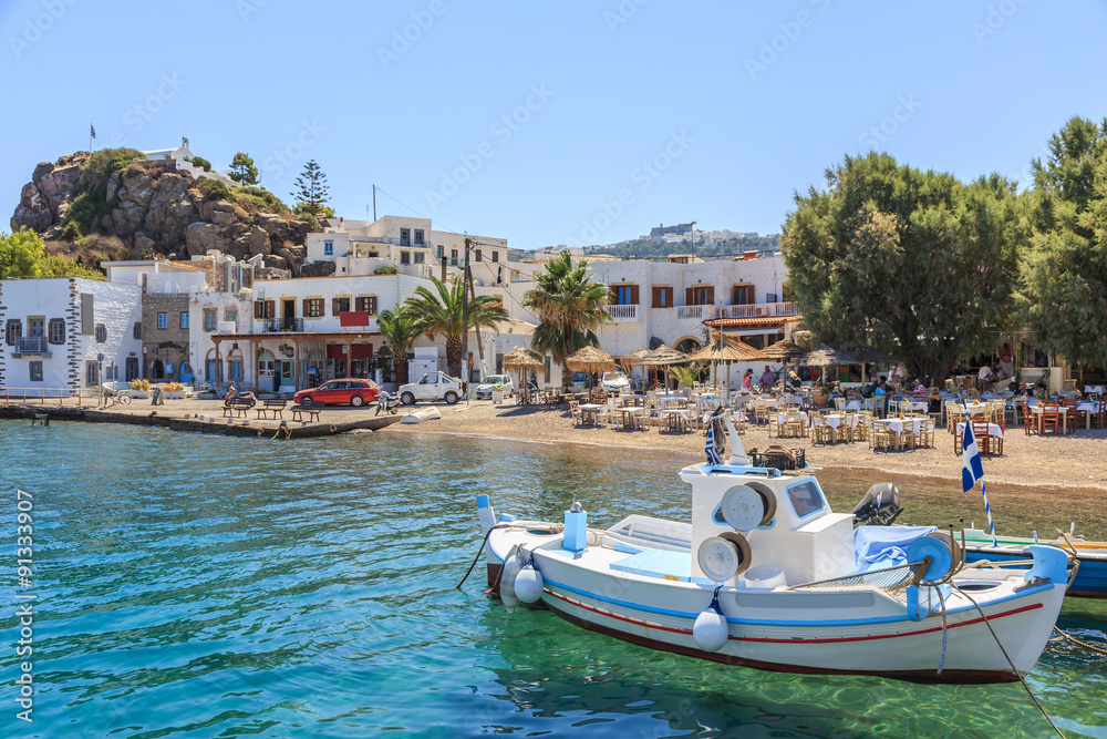 Greek island of Patmos belongs to the Dodecanese. Fragment of the fishing port and beach in the town of Skala. On the hill visible town Chora and Monastery of St. John's