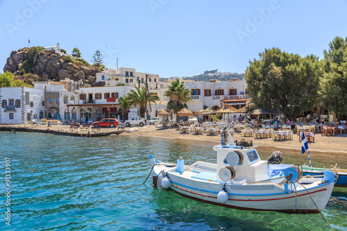 Greek island of Patmos belongs to the Dodecanese. Fragment of the fishing port and beach in the town of Skala. On the hill visible town Chora and Monastery of St. John's