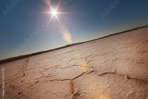 Dry lake under a blue sky and sun