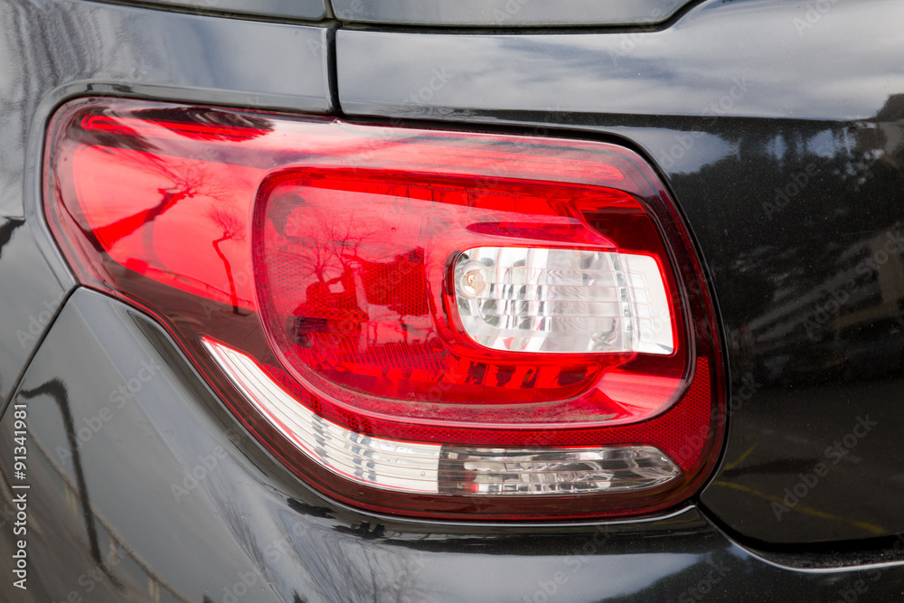 Detail of the rear end of a silver car with focus on the brake lights
