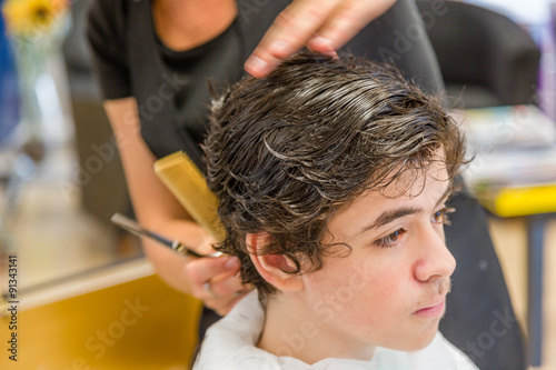 teenage boy sitting at the hairdresser salon for a haircut