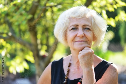 Mature, blonde woman in garden,
