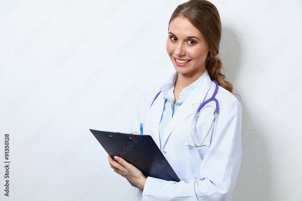 Friendly smiling young female doctor, standing near wall Friendly smiling young female doctor, standing near wall