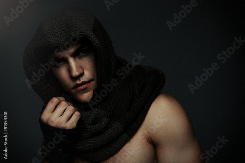Fashion man portrait wearing knitted scarf on had on dark background photo