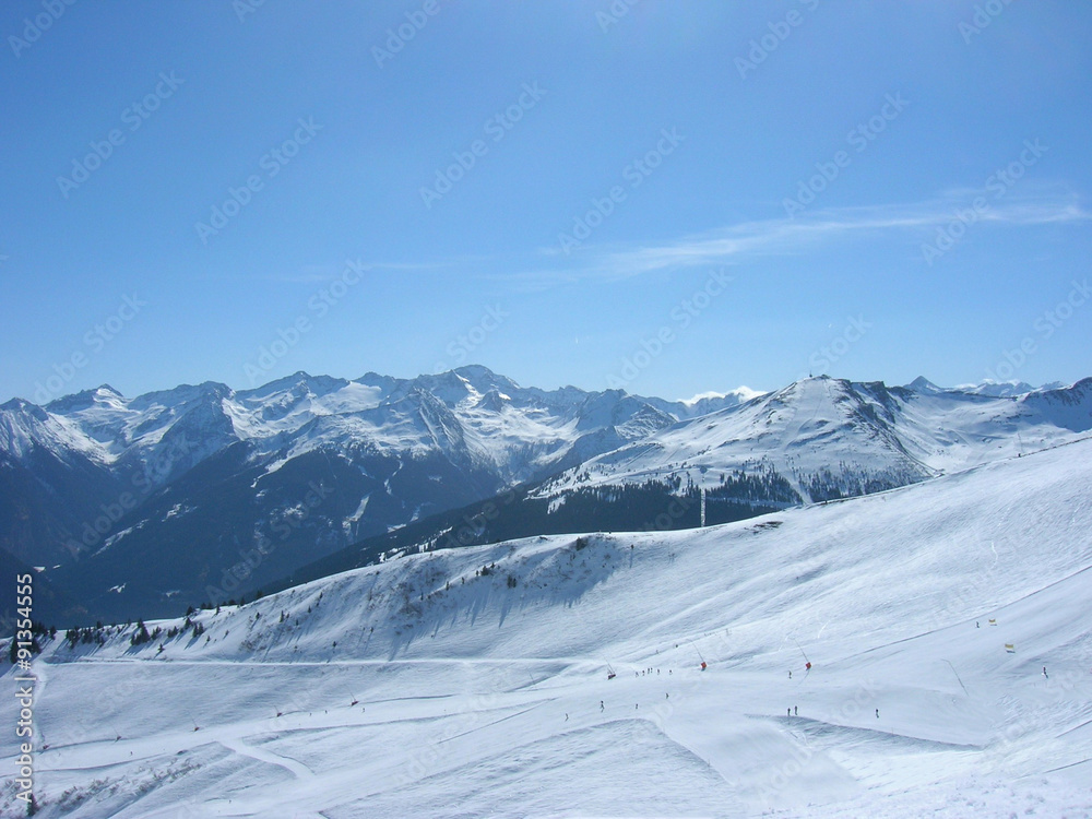 Beautiful idyllic snowy winter landscape in a mountain ski resort, on a sunny afternoon. Panoramic view.