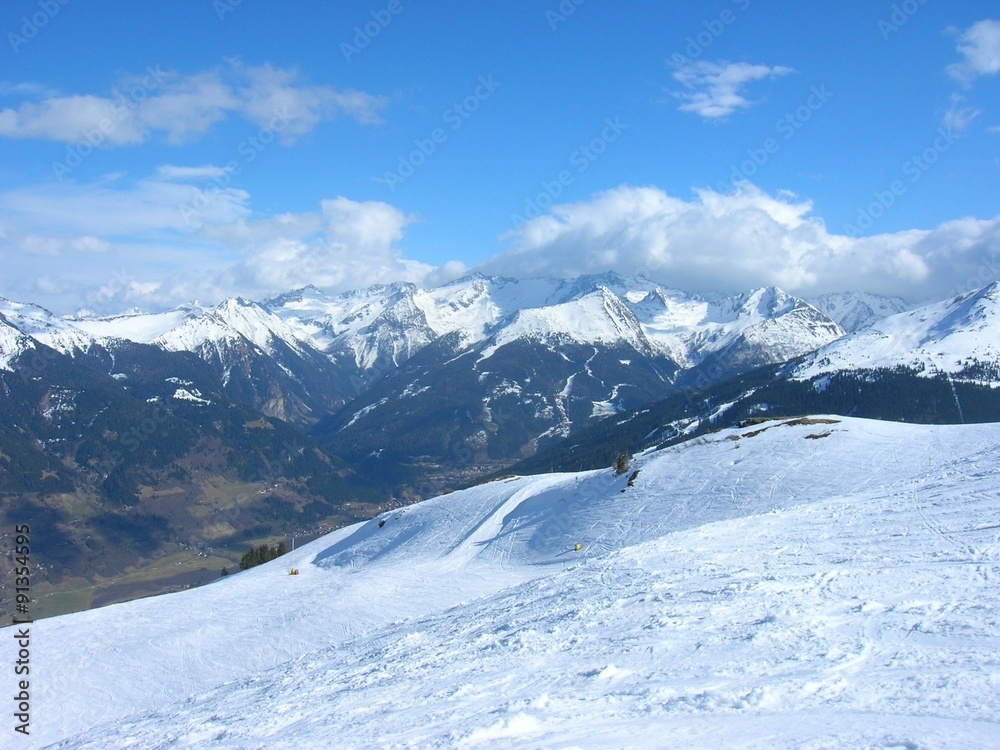 Beautiful snowy winter landscape in a mountain ski resort, on a sunny afternoon. Ski slopes, panoramic view.