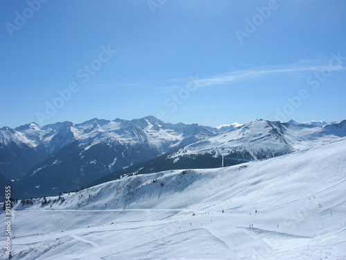 Beautiful idyllic snowy winter landscape in a mountain ski resort, on a sunny afternoon. Panoramic view. © Jasmina