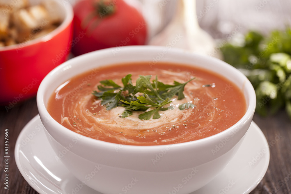Delicious tomato soup with aromatic spices on a wooden table.