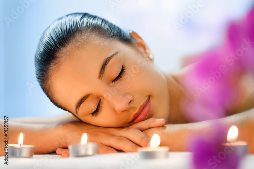 Young woman relaxing in dimmed candle light after massage.
