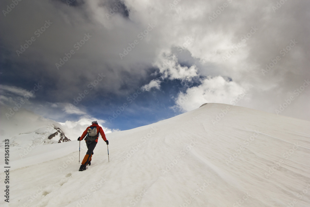 man climbing on a snowy mountain with poles 