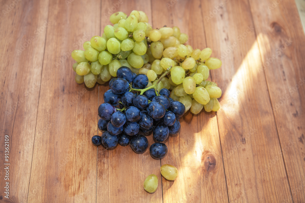 Green and purple round grapes on old wooden table, selective foc Green and purple round grapes on old wooden table, selective foc