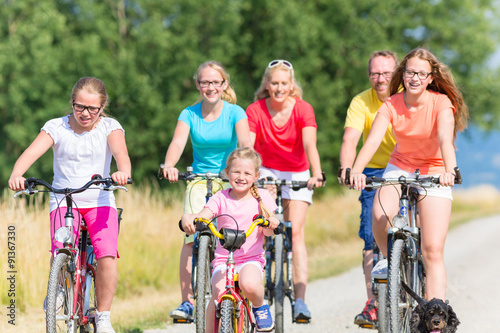 Familie fährt Fahrrad auf Feldweg, Mutter, Vater und Kinder gemeinsam