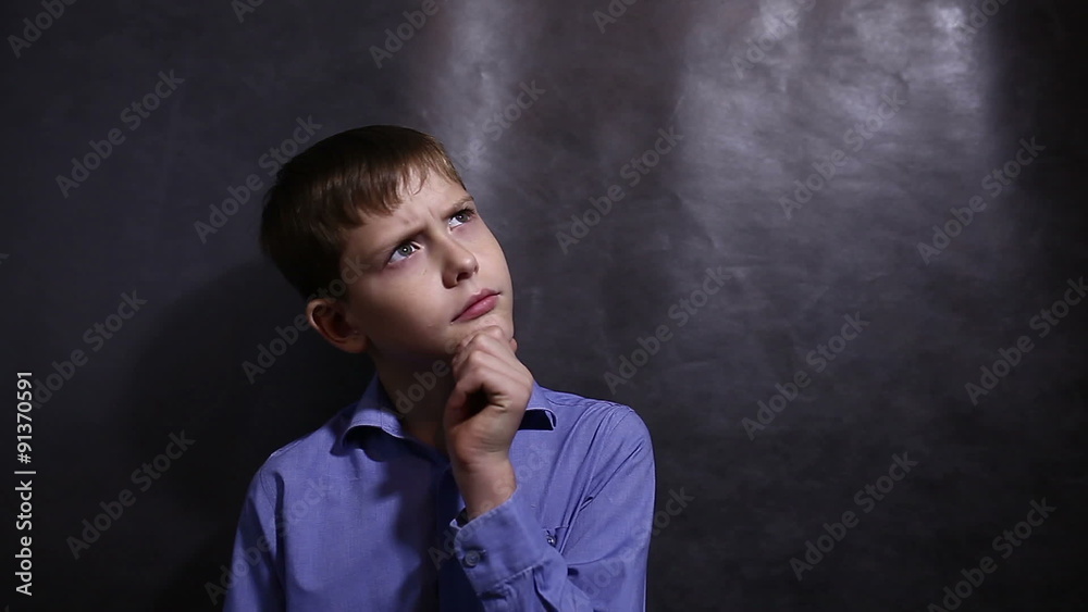 Teenage boy in a blue shirt is thinking looking away scratching Teenage boy in a blue shirt is thinking looking away scratching
