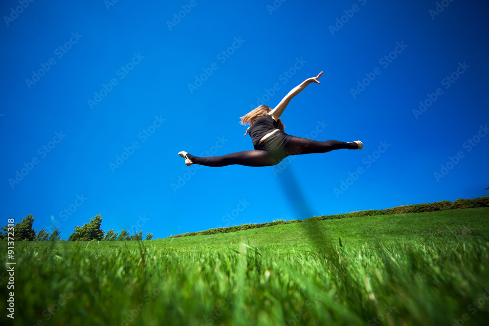 Smiling young gymnast is jumping in split and floating above the Smiling young gymnast is jumping in split and floating above the