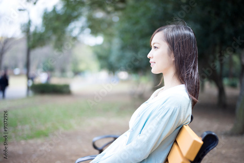 公園のベンチに座る女性 © blanche