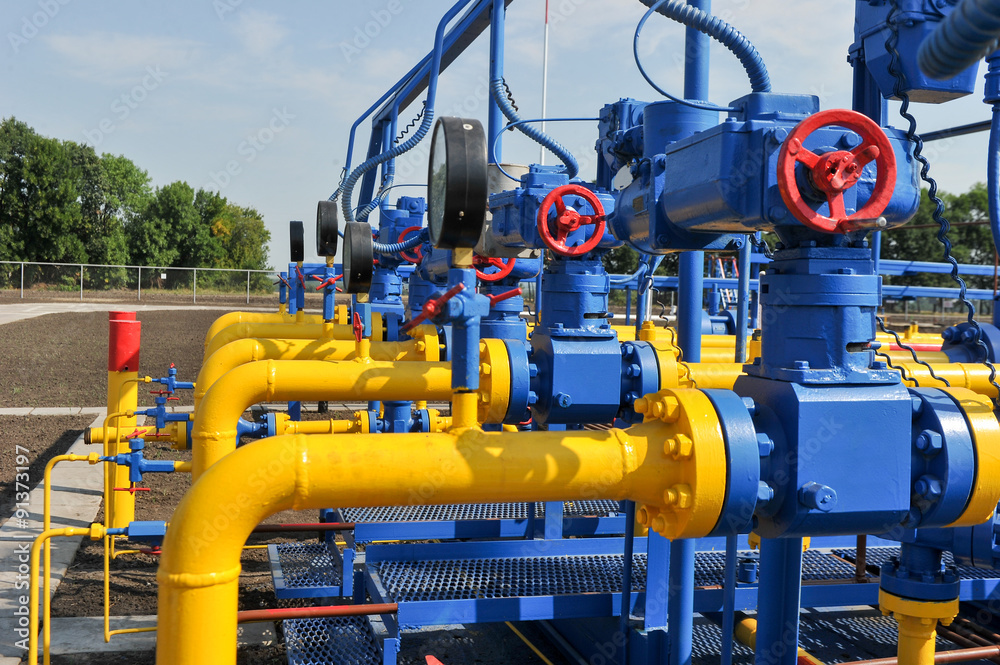 Red faucet with steel pipe in natural gas treatment plant in bright sunny summer day Red faucet with steel pipe in natural gas treatment plant in bright sunny summer day