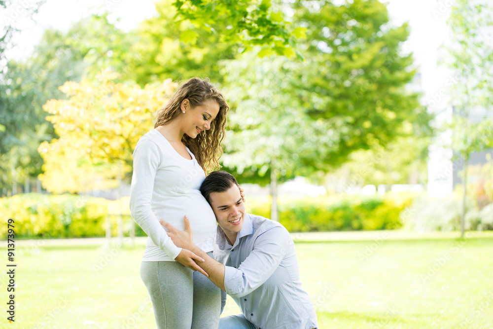 Happy and young pregnant couple in park in summer Happy and young pregnant couple in park in summer