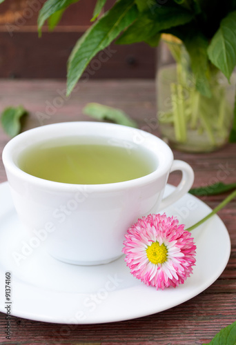 Cup of herbal tea with wild camomiles, mint and flowers