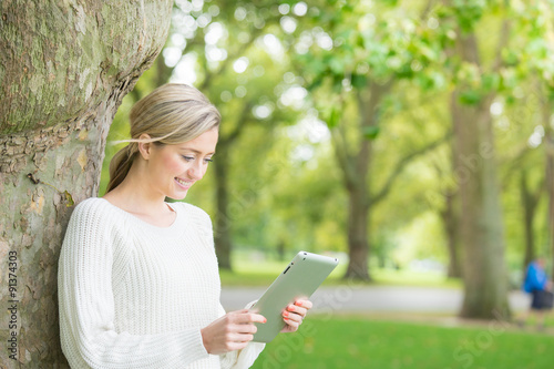 Young woman using tablet & mobile phone in the park