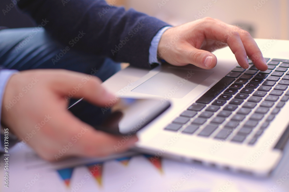 Businessman at a table with a smartphone and a laptop Businessman at a table with a smartphone and a laptop