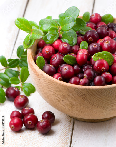 Cowberry with green leaflets in wooden cup