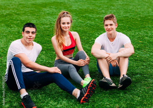 Young sports people sitting on the grass