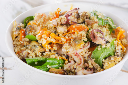 Salad with quinoa and seafood in a white bowl.