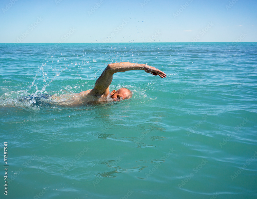 A man swims in the open sea