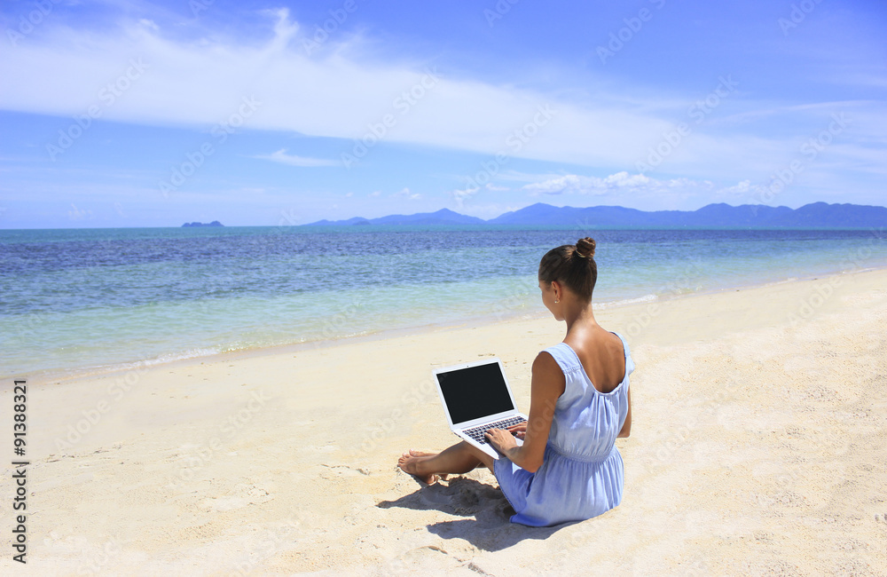 Bussines woman working on the beach with a laptop, she is a freelancer