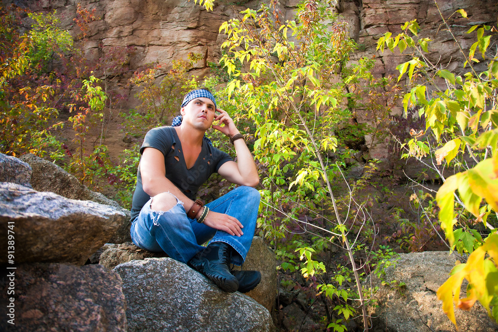 Man rests in the nature sitting on a stone