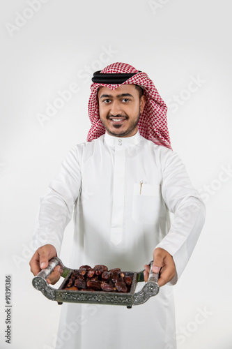 Portrait of Arab man holding dates on tray. photo