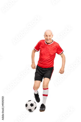 Fototapeta Naklejka Na Ścianę i Meble -  Senior man in a red jersey playing football