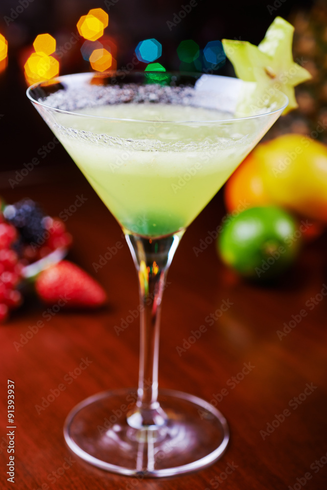 glass of bright tropical alcohol cocktail or lemonade with beautiful decoration on a table in a restaurant with backgrounds of bright colored lights. soft focus.