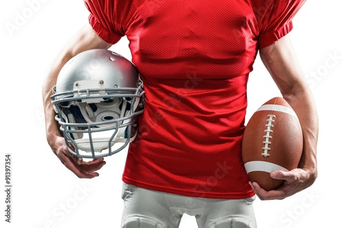 Midsection of American football player holding helmet and ball