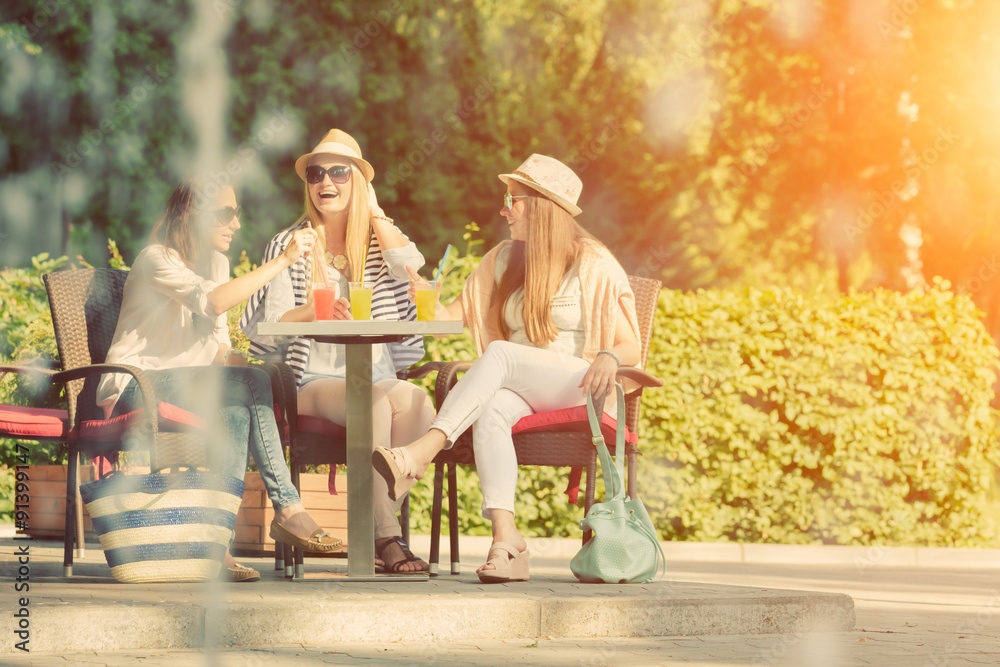 Three attractive girlfriends enjoying cocktails in an outdoor cafe, friendship concept Three attractive girlfriends enjoying cocktails in an outdoor cafe, friendship concept