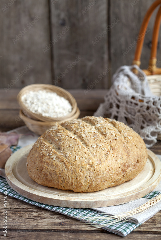 Homemade oatmeal bread with whole wheat flour on the old wooden table. Selective Focus, rustic style.