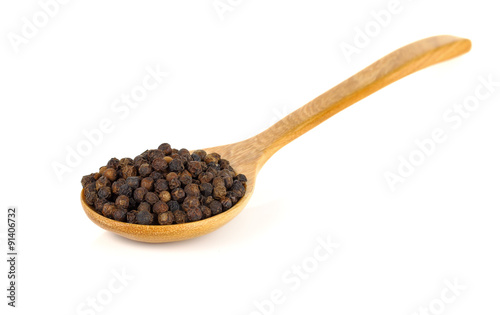 Wooden spoon and black peppercorn on white background