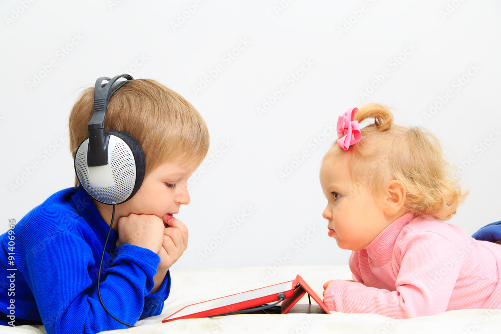 little boy and toddler girl with headset using touch pad little boy and toddler girl with headset using touch pad