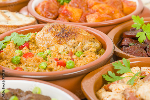 Arroz Con Pollo - Chicken and rice cooked with sofrito and beer. Surrounded by other tapas dishes. photo
