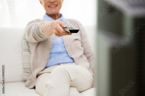 close up of happy senior woman watching tv at home