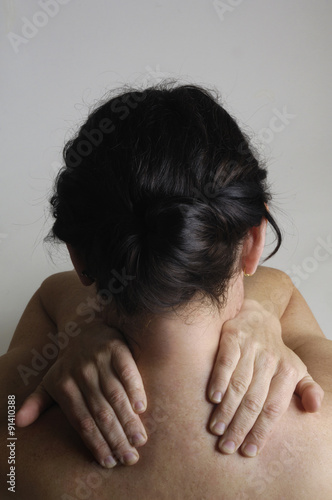 Nude woman with back pain on a gray background