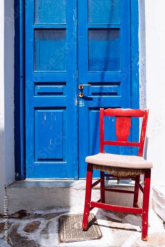 Detail of colorful blue door and red wooden chair