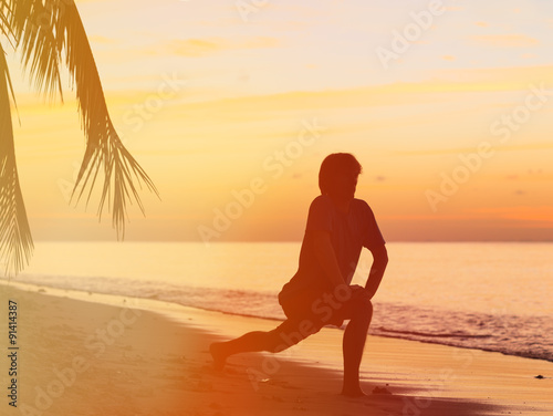 Silhouette of young man doing yoga at sunset beach