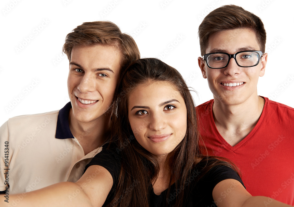 Attractive teenage friends making selfie looking at camera. Smiling people with smartphone photographing themselves. 