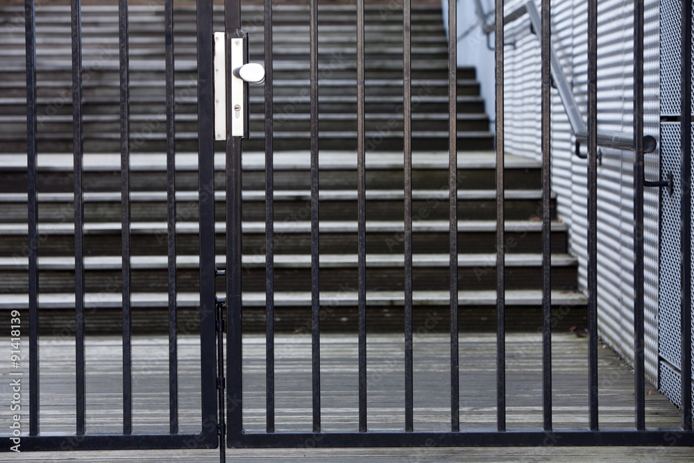 Closed security gate with a staircase in the background Closed security gate with a staircase in the background