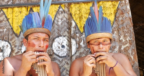 Native Brazilians playing wooden flute at an indigenous tribe in the Amazon photo