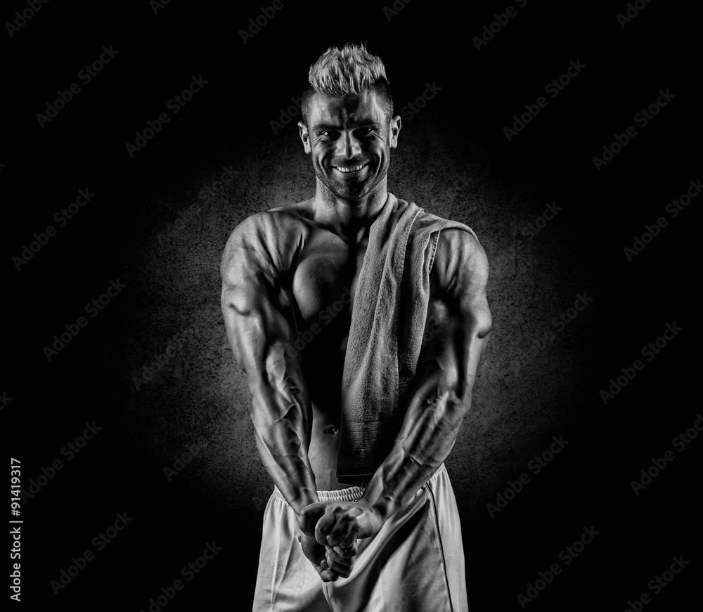 Healthy muscular young man after a workout on dark background