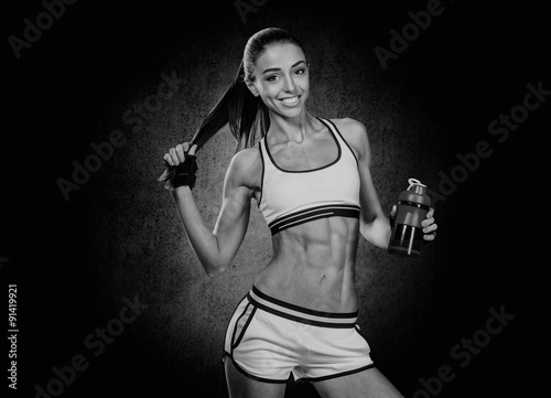 athletic young woman with water bottle in hand on a black backgr