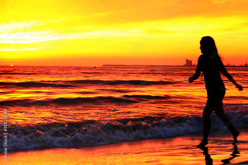 Silhouette of woman, running on sunset along ocean coast
