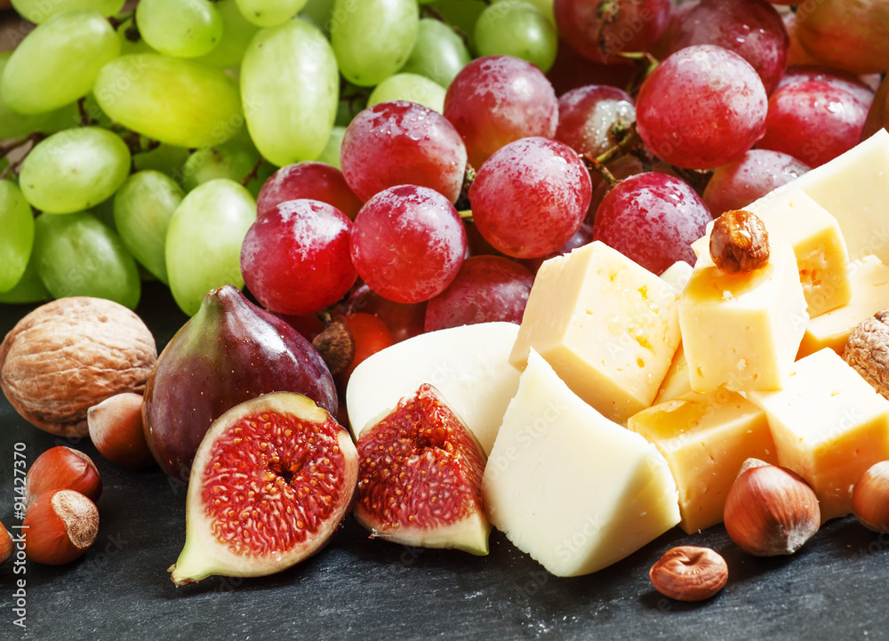 Snack plate for wine: cheese, green and pink grapes, figs, nuts Snack plate for wine: cheese, green and pink grapes, figs, nuts